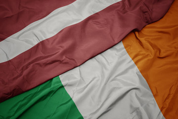 waving colorful flag of ireland and national flag of latvia.