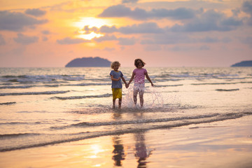 Child playing on ocean beach. Kid at sunset sea.