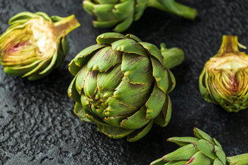 Fresh raw organically grown artichoke flower buds on dark background