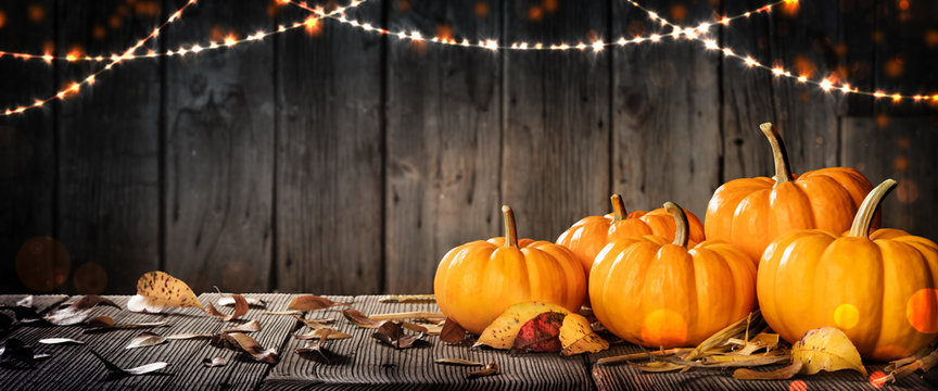 Thanksgiving Pumpkins And Leaves On Rustic Wooden Table With Lights And Bokeh On Wood Background - Thanksgiving / Harvest Concept