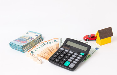 Finance and car loan, saving money for a car. Red car and euro banknotes. Calculator, euro money and House. Wooden cubes with word loan. Copy space for text. Loan payment car and house.