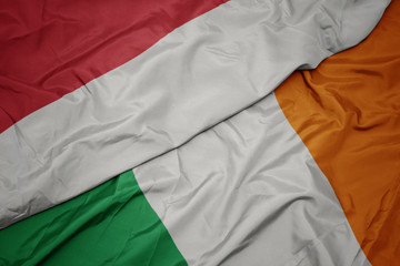 waving colorful flag of ireland and national flag of indonesia.