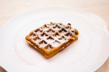 Delicious waffle with powdered sugar on a dessert plate
