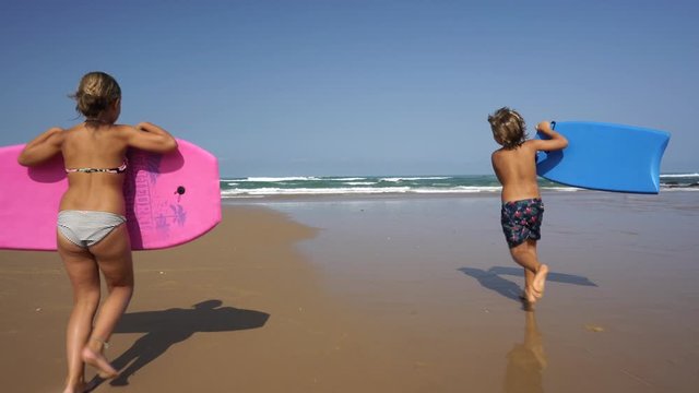 Kids riding bodyboards in ocean waves
