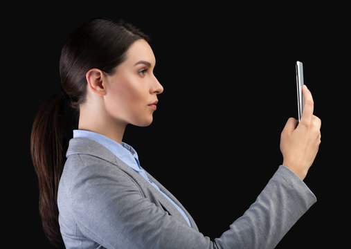 Businesswoman Holding Smartphone Using Face Recognition System Over Black Background - Powered by Adobe