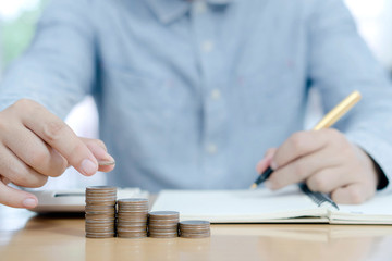 Business man putting coin on pile of money saving bank and account for his money all in finance accounting concept.