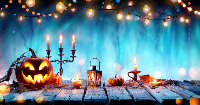 Smiling Pumpkin And Candelabrum On Table In Spooky Forest