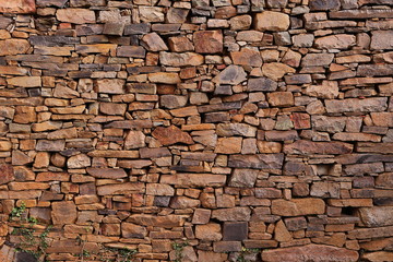 OLD STONE BRICK WALL OF MULTIPLE SHAPES MADE BY HAND