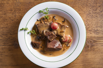 Braised veal cheeks in cream sauce with mushrooms. View from above, top studio shot - horizontal