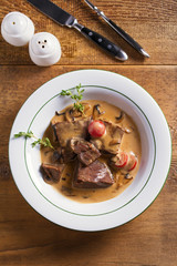 Braised veal cheeks in cream sauce with mushrooms. View from above, top studio shot