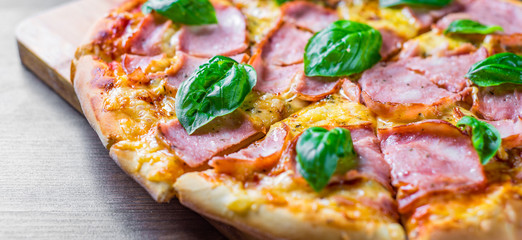 Pizza with Mozzarella cheese, ham, tomato sauce, pepper, Spices and Fresh basil. Italian pizza on wooden table background