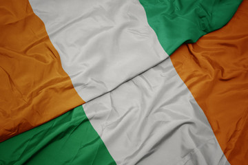 waving colorful flag of ireland and national flag of cote divoire.