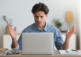 Shocked Man Looking At Laptop Having Problem Working At Home
