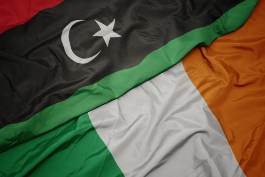 waving colorful flag of ireland and national flag of libya.