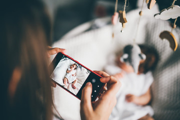 Mother taking a picture of A baby with a mobile phone.