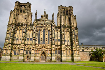 Fototapeta na wymiar Sun on stone sculptures on the West front facade of Wells Cathedral after a rain storm Wells England