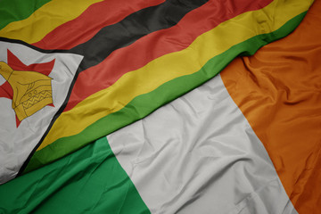 waving colorful flag of ireland and national flag of zimbabwe.