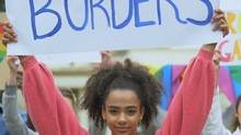 Biracial girl holding Love without borders poster together with LGBT activists