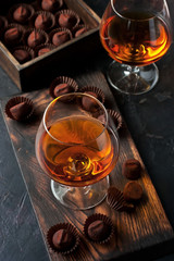 Glass of brandy  or cognac and  chocolate truffles on dark table