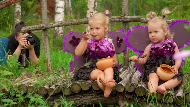 Girls pretend to be butterflies for photo shooting. Photographer makes pictures of girls with butterfly wings 