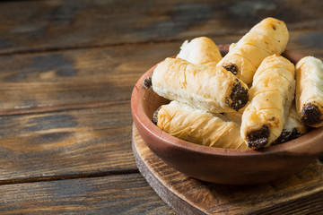 Puff rolls with poppy seeds in a wooden bowl on a wooden table. Sweet pastries