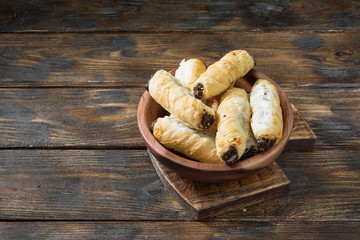 Puff rolls with poppy seeds in a wooden bowl on a wooden table. Sweet pastries