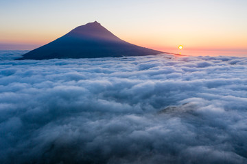 Aerial image with magical sunset over a low cloud layer covering Pico Island, with Ponta do Pico (Mount Pico)