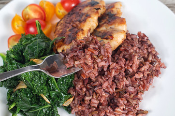 Healthy organic rice plate with white chicken meat, kale and cherry tomatoes