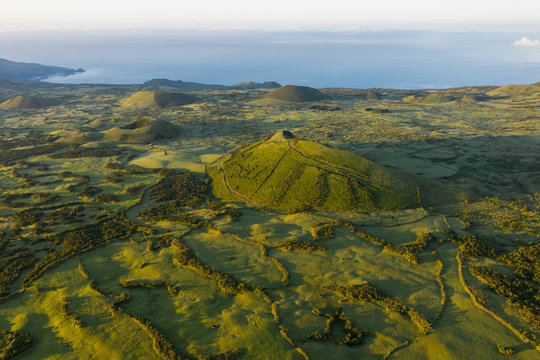 Aerial image of typical green volcanic caldera crater landscape with volcano cones of Planalto da Achada central plateau of Ilha do Pico Island, Azores