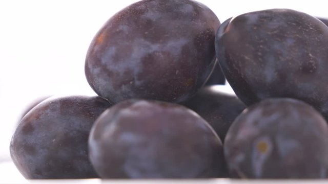 Fresh ripe damson plums on white background rotating close-up.