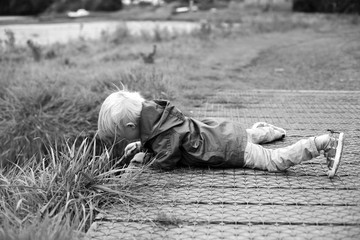 Child lying on a bridge looking over the edge