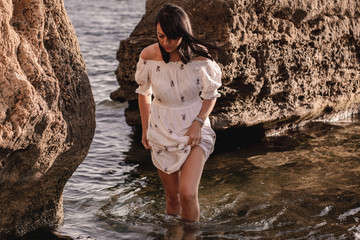 Fototapeta premium beautiful young brunete woman enjoys the beautiful view on the beach and has a good sunrise time. Relax