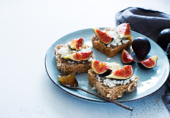 Open sandwiches with soft cheese and figs on a blue plate