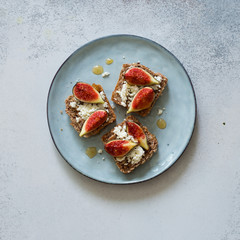 Open sandwiches with soft cheese and figs on a blue plate