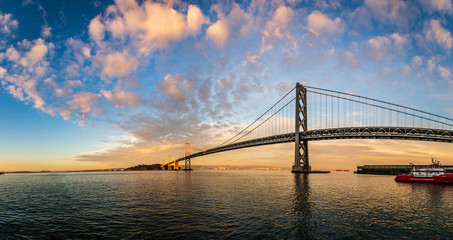Colorful panorama of the San Francisco bay bridge arching across the water at sunset