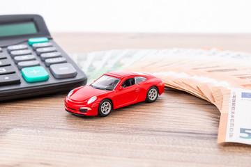 Insurance, loan and buying car concept. Red car and euro banknotes. Calculator, euro money and red car. Copy space for text. Calculatin cost of car.