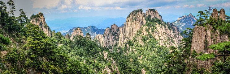 Fototapeta na wymiar Panorama with pine trees in the foreground and rough rocky peaks leading to the horizon in Huang Shan (黄山, Yellow Mountains) China