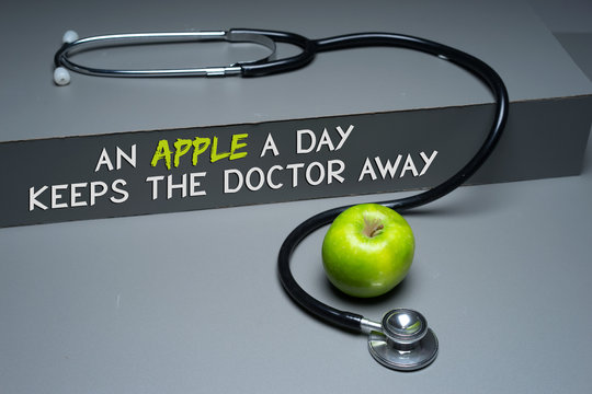 An apple a day keeps the doctor away concept. Stethoscope and green apple concept for diet, healthcare, nutrition or medical insurance on grey based background. 