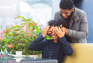 Black man standing behind his woman and closing her eyes