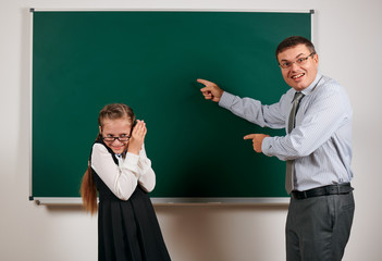 angry teacher shout to schoolgirl, posing at blackboard background - back to school and education...