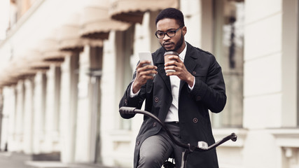 Happy businessman using mobile phone, drinking coffee outdoors