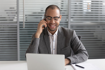 Happy african american businessman talking on cellphone with corporate client.