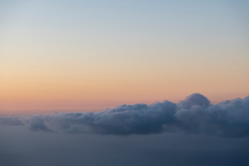 Obraz premium scenic image of a layer of clouds haging over the sea after sunset with a pink sky