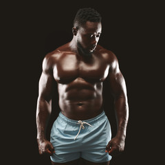 Fototapeta premium Strong athletic black man posing at studio, demonstrating muscular body