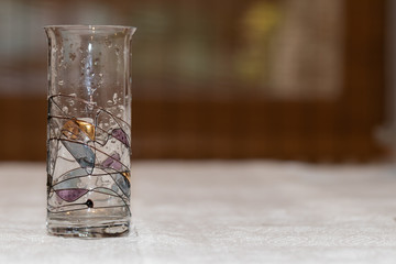 Tall glass of thin glass decorated with colored lines with drops