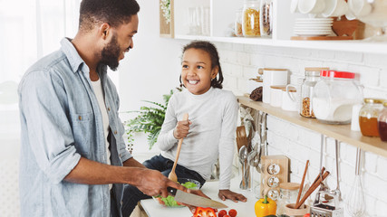 Cute little girl assisting her dad in making healthy dinner