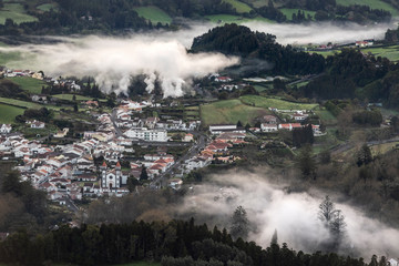 Fototapeta premium Village of Furnas at sunrise with a fog mist of gases and steams from several fumaroles, calderas and thermal pools.