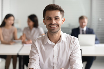 Portrait of smiling young team leader sitting at office.