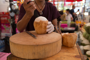 a man cuts a fresh coconut, preparing it to sell on a fruite stand, Tahiland