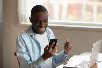 Excited biracial man feel overjoyed with good news on cellphone